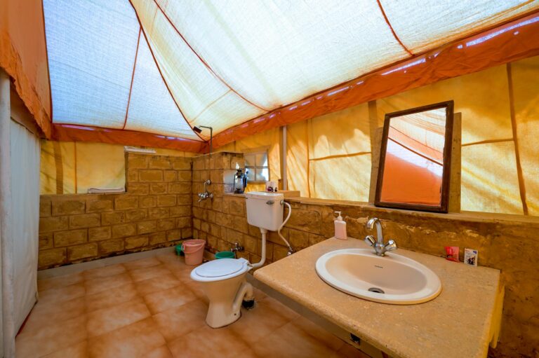 A rustic tent bathroom setup with brick walls and essential amenities in Jaisalmer, India.