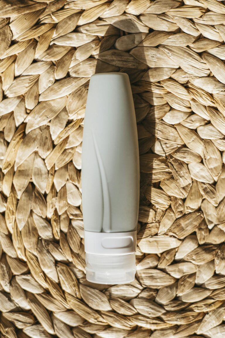 A silicone travel bottle lies on a wicker mat, perfect for travel and toiletries.